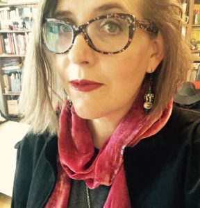 A woman, Jennifer Finstrom, wearing glasses and a red scarf