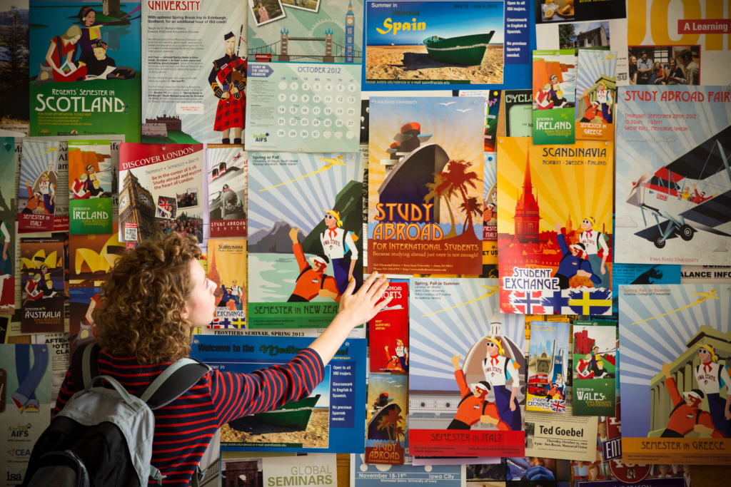 A female student looking at a collection of study abroad posters.