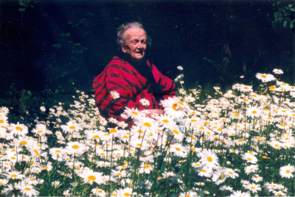 An elderly woman surrounded by daisies