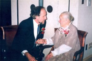 An elderly woman and a younger man speaking together