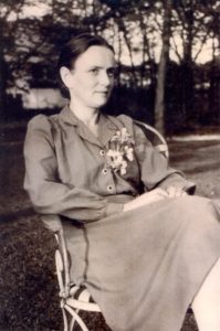 Black and white photograph of a woman sitting in a yard.