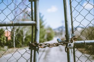 Two sides of a chainlink fence entrance are chained closed.