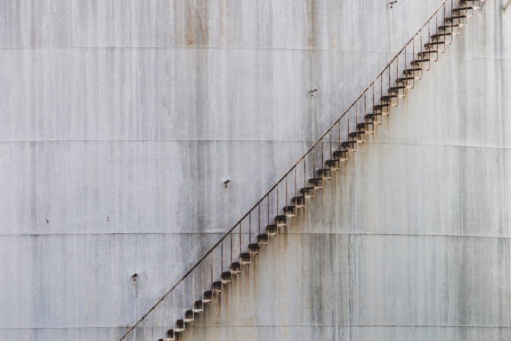 A steep steel staircase ascends an industrial silo.