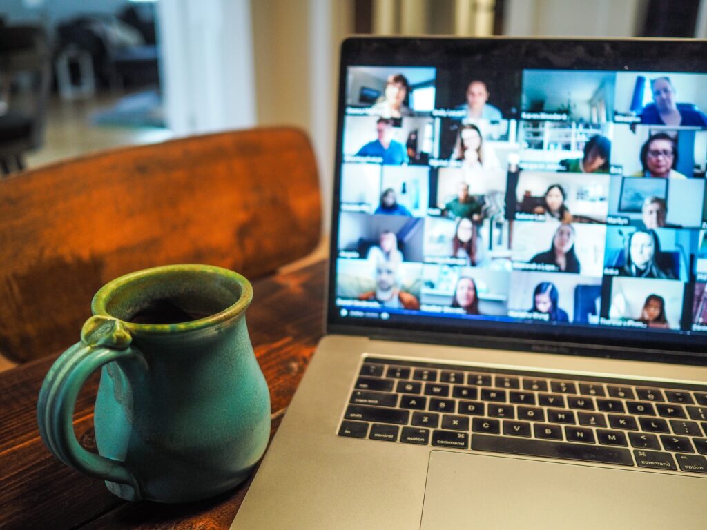 Macbook computer open to a Zoom screen with a mug of coffee next to it.