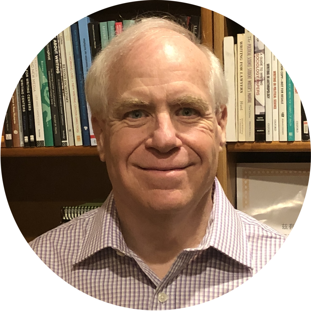 Brad Hughes smiling and standing in front of a bookcase