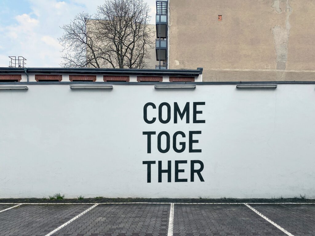 a white wall with stenciled letters reading "COME TOGETHER"