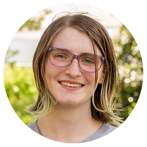 author Ava Hutt smiles at the camera while wearing light purple-framed glasses