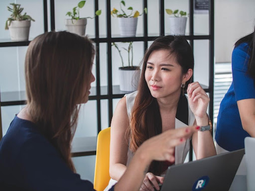 Two women having a conversation in front of a lap top