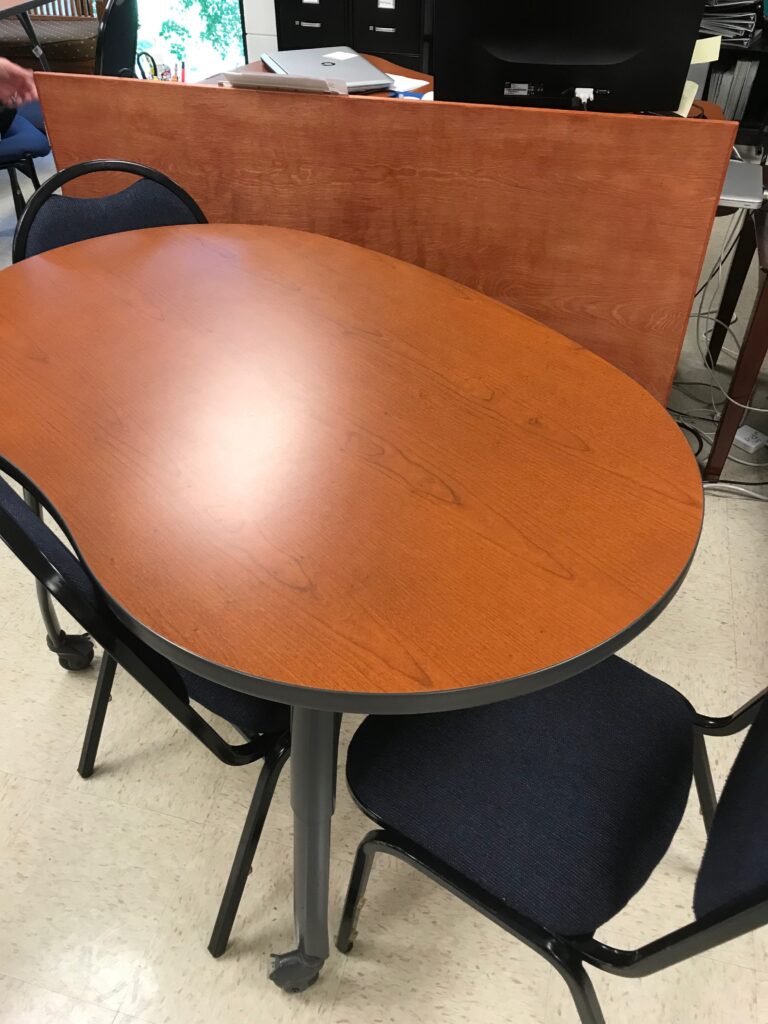 a kidney-shaped table with several chairs surrounding it