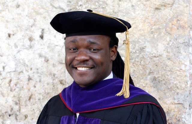 Professor Tinashe Hofisi wears academic garb and smiles at the camera