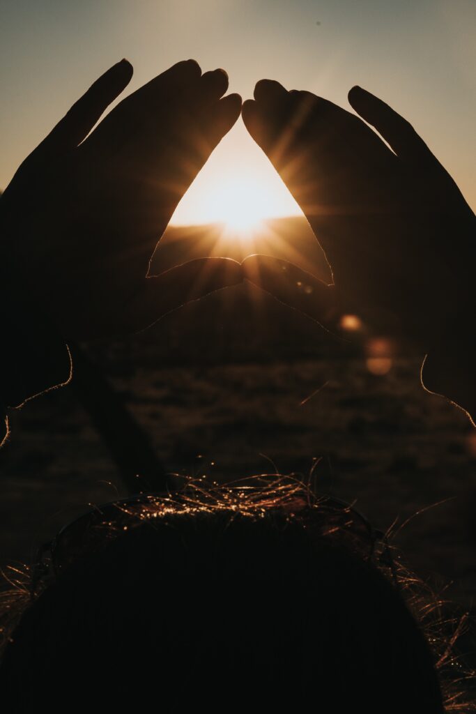 close up of hands making a triangle framing the sun