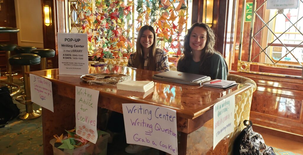 Image of two consultants sitting at a table with writing center materials