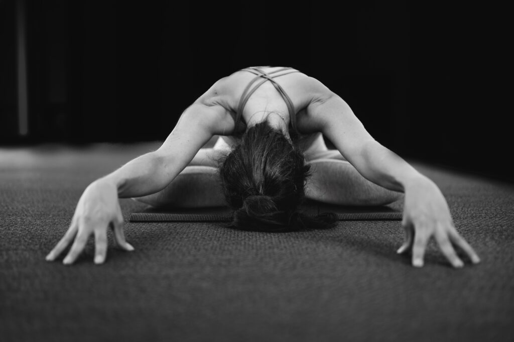 Woman sitting in yoga pose with body bent forward to the ground