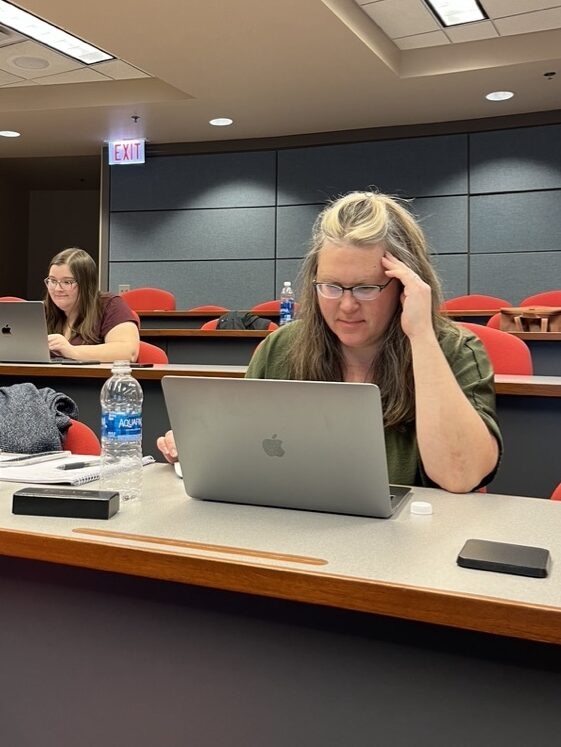 A contributor who is writing diligently at her Macbook. 