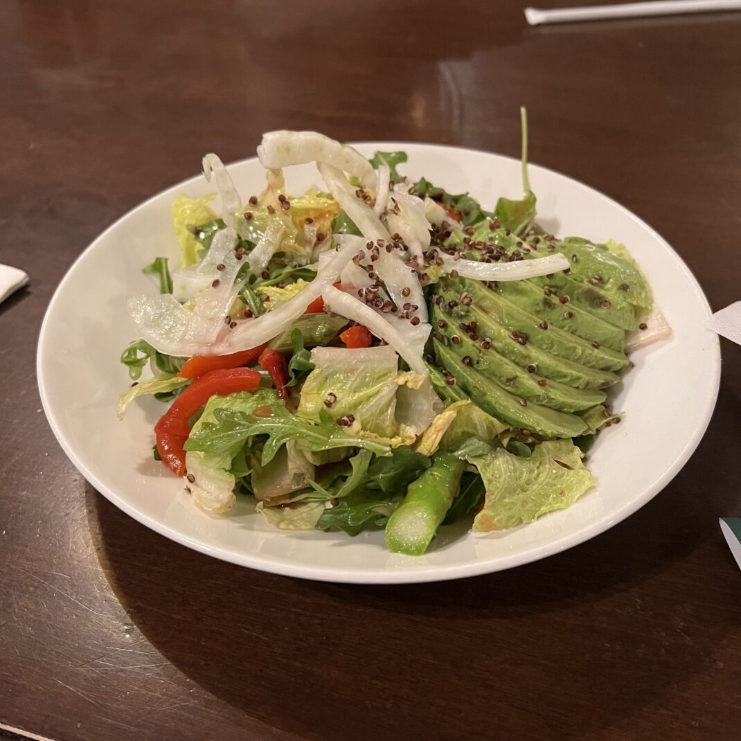 a green salad with sliced avocados