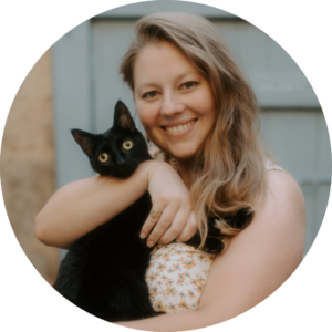 Lucy McInerney smiling widely and holding a black cat.