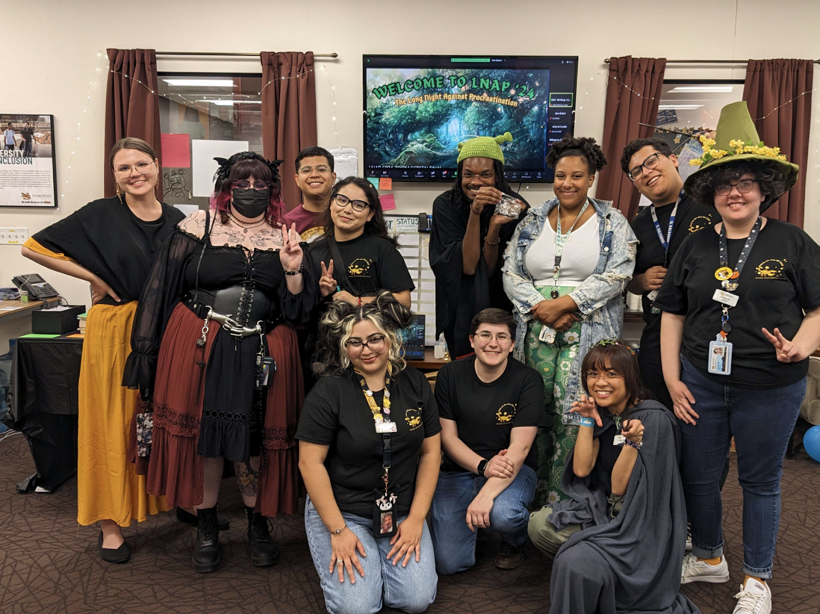 Eleven student-colleagues pose and smile in the Writing Center. Some wear costumes.