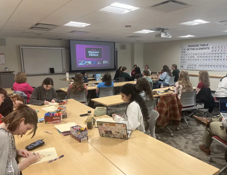 Undergraduate writing tutors in a classroom drawing and playing games together.