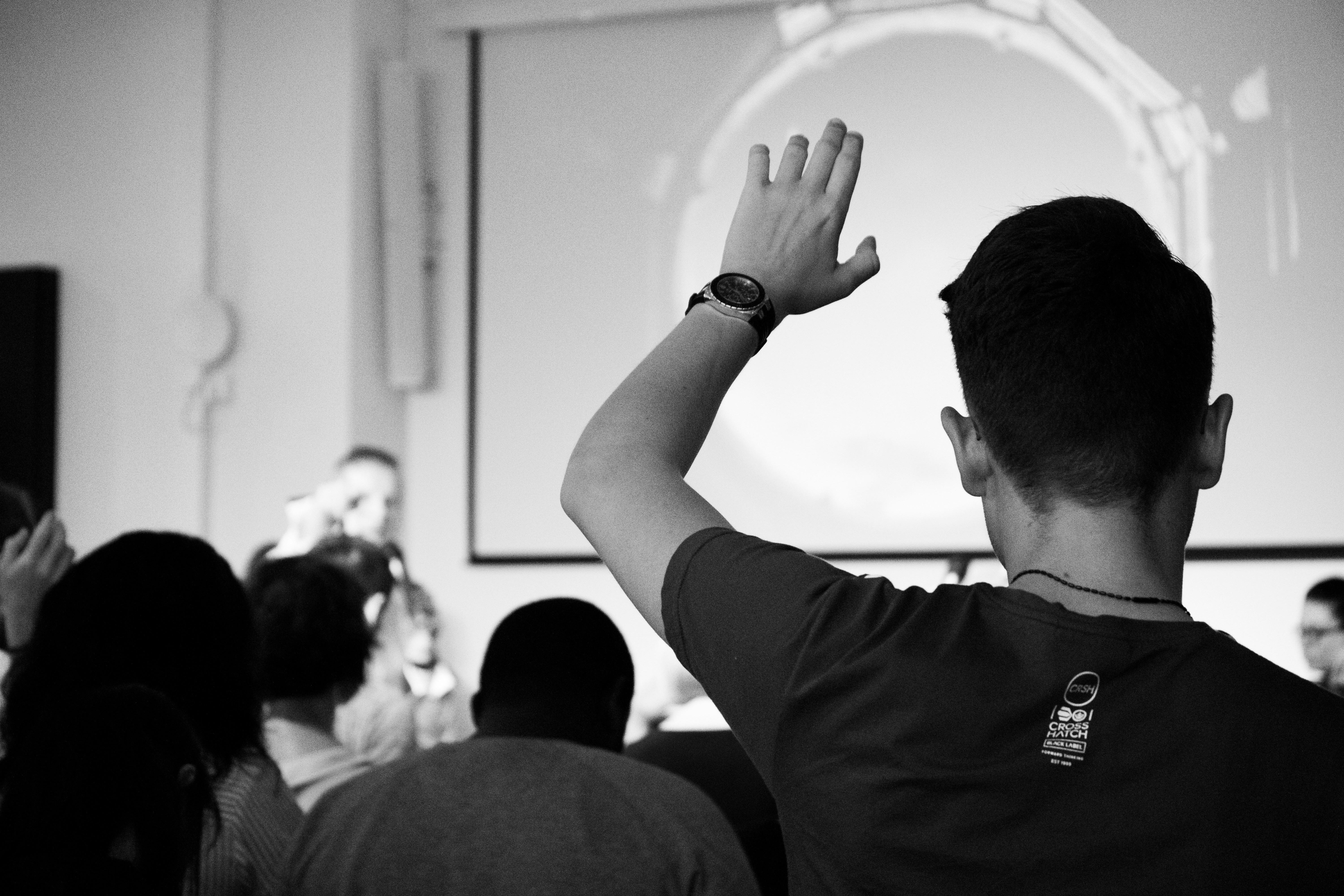 A person raising his hand in front of a group of people