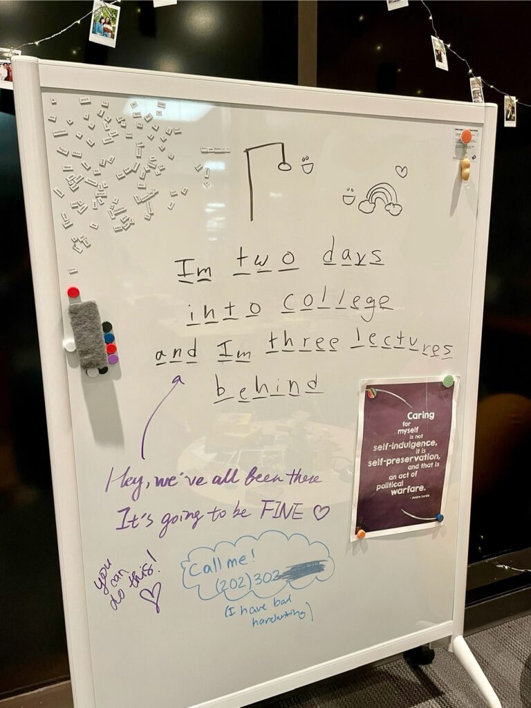 A student wrote “Im two days into college and Im three lectures behind” on a whiteboard. There are supportive messages written in response to the writing.