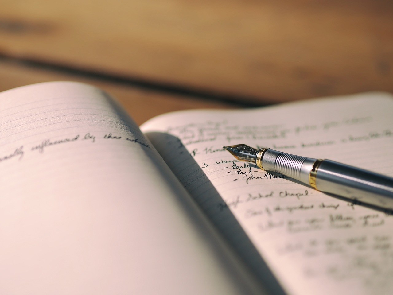 An open notebook with a pen resting on top