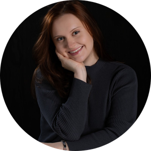 Author photo of Annalee. She is resting her head in her hand and smiling.