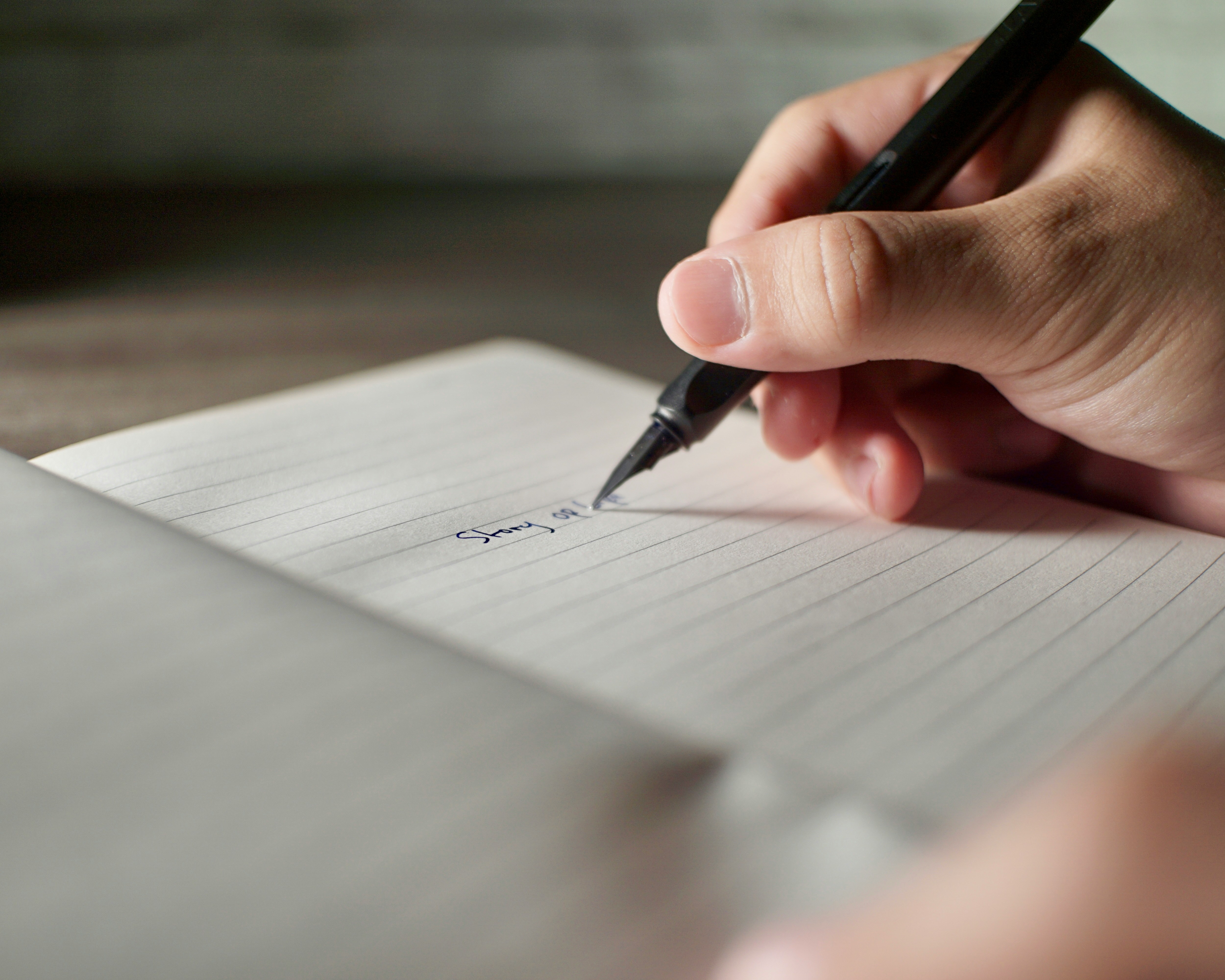a hand penning the first line on a fresh journal page