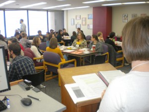 A room filled with people sitting around shared tables 