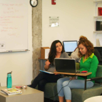 the open space of the asc writing center with two women seated working on writing