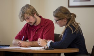 A writing center tutoring session at the Notre Dame Writing Center. Two individuals sit at a table together looking at a piece of writing.